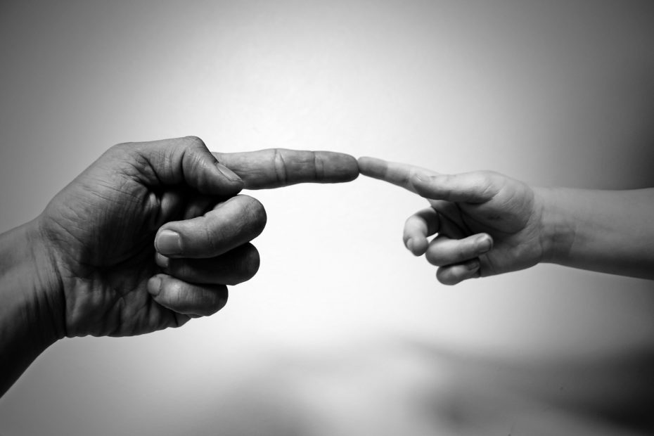 Zeigefinger einer Erwachsenenhand berührt Zeigefinger einer Kinderhand